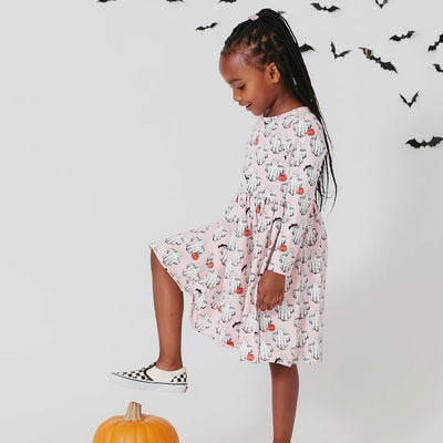 little girl modeling the boo dress, long sleeve light pink with ghosts all over it, some ghosts are holding pumpkins and others a bat