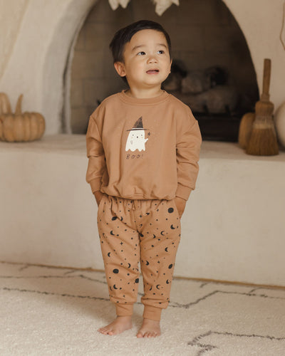 kids halloween sweatsuit, 2 piece set: relaxed sweatshirt with a ghost and witch hat and relaxed sweatpants with night sky print all over the sweat pants. Little boy modeling the sweatsuit. 