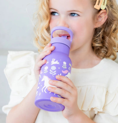 Little girl drinking from purple water bottle. The bottle has unicorns jumping over rainbows. 