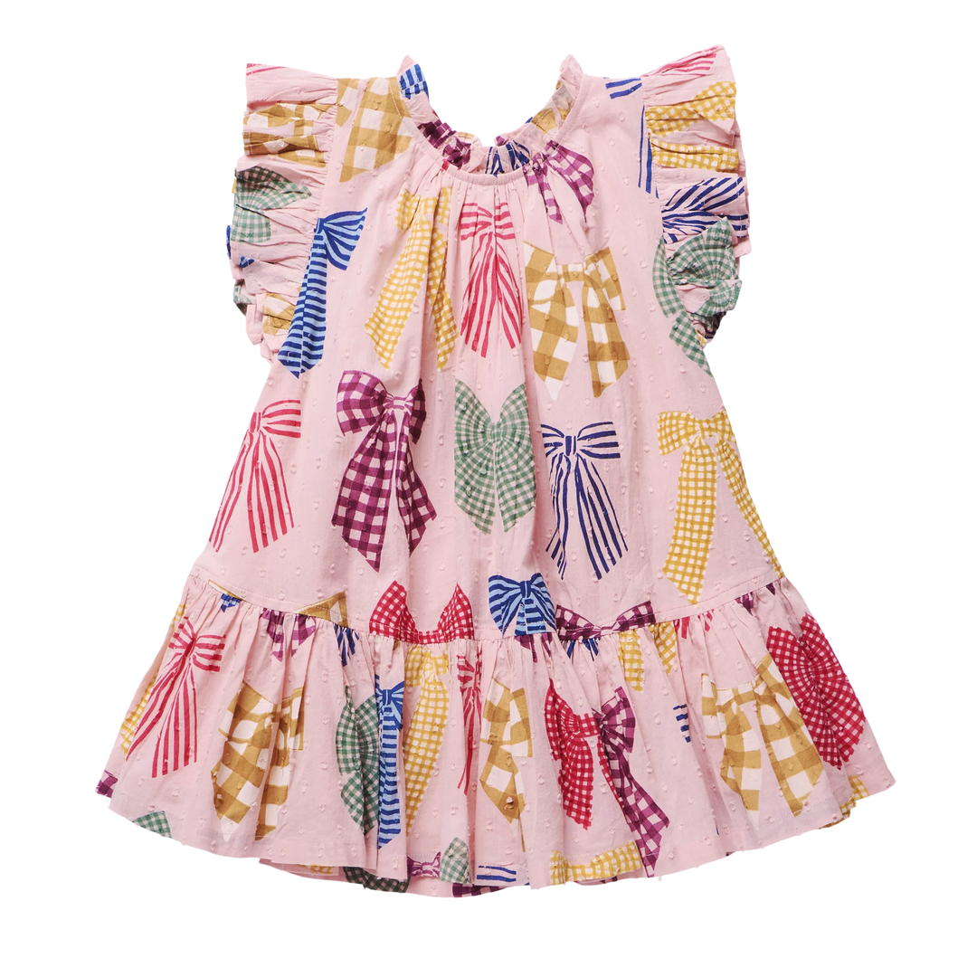 A pink sleeveless dress for toddlers or girls, featuring a playful print of colorful ribbon bows in various patterns (stripes, gingham, polka dots) on a solid white background.
