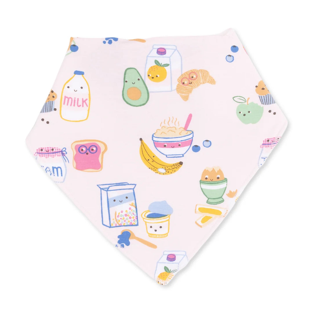 A light pink baby bandana bib featuring a cute, colorful cartoon breakfast pattern with illustrations of milk bottles, croissants, avocado, yogurt, and cereal.