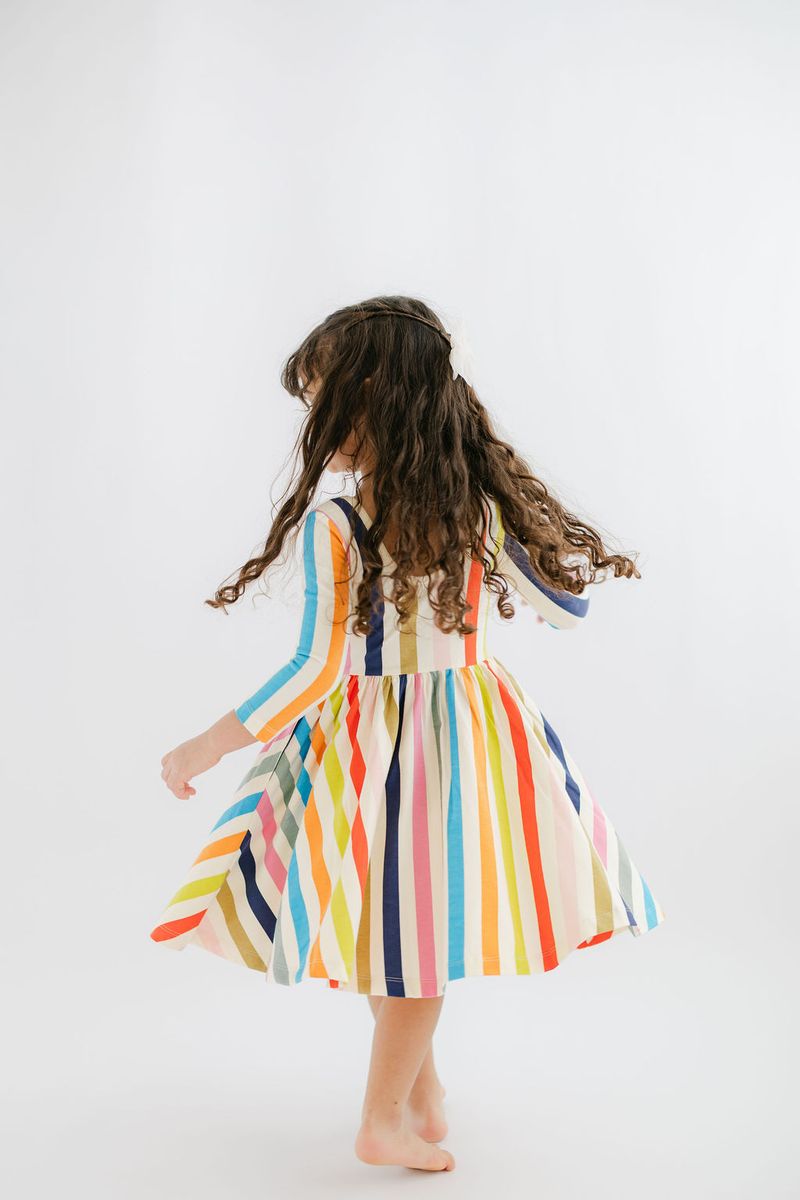 Child wearing a colorful striped dress on a white background