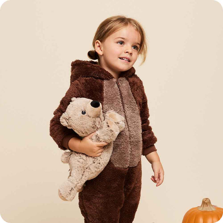Child wearing a brown bear-themed outfit holding a teddy bear against a beige background