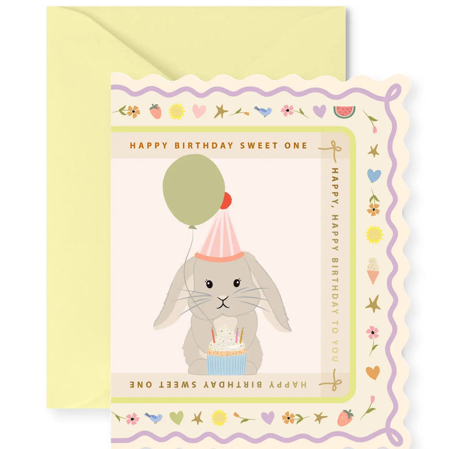 Birthday card with a rabbit holding a balloon and cake, on a yellow envelope.