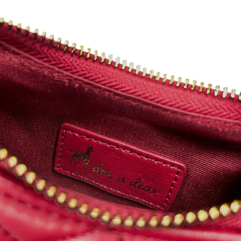 Close-up of a red bag with a gold zipper and 'doe a dear' label.