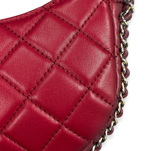 Close-up of a burgundy quilted handbag with a chain detail on a white background