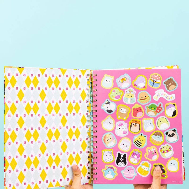 Open notebook with yellow diamond pattern on left page and colorful stickers on right page against a light blue background