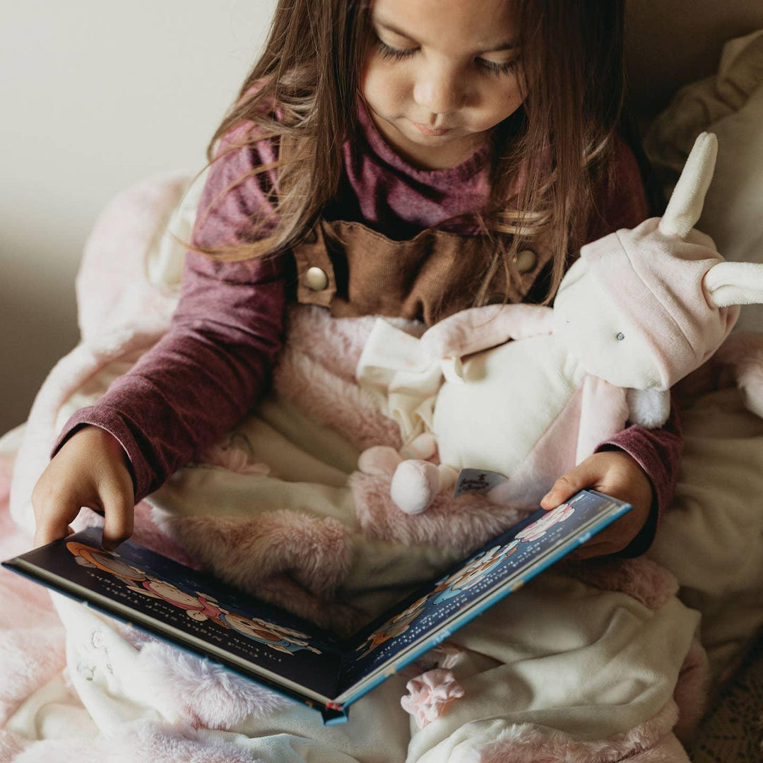 little girl holding a white bunny with pink arms and legs and wearing a pink hat with pom pom. 