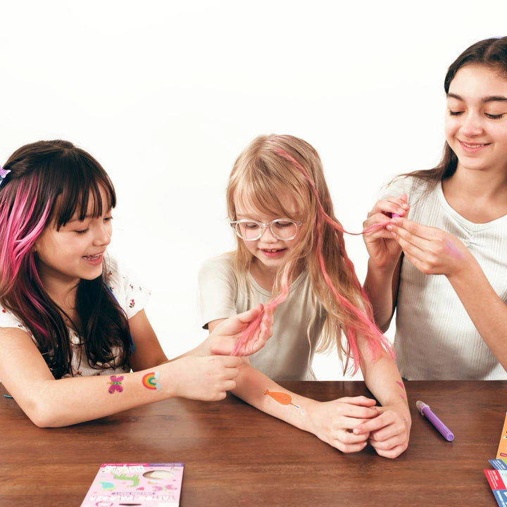 this picture shows little girls adding fun colors to their hair. the girl's each have pink highlights. 