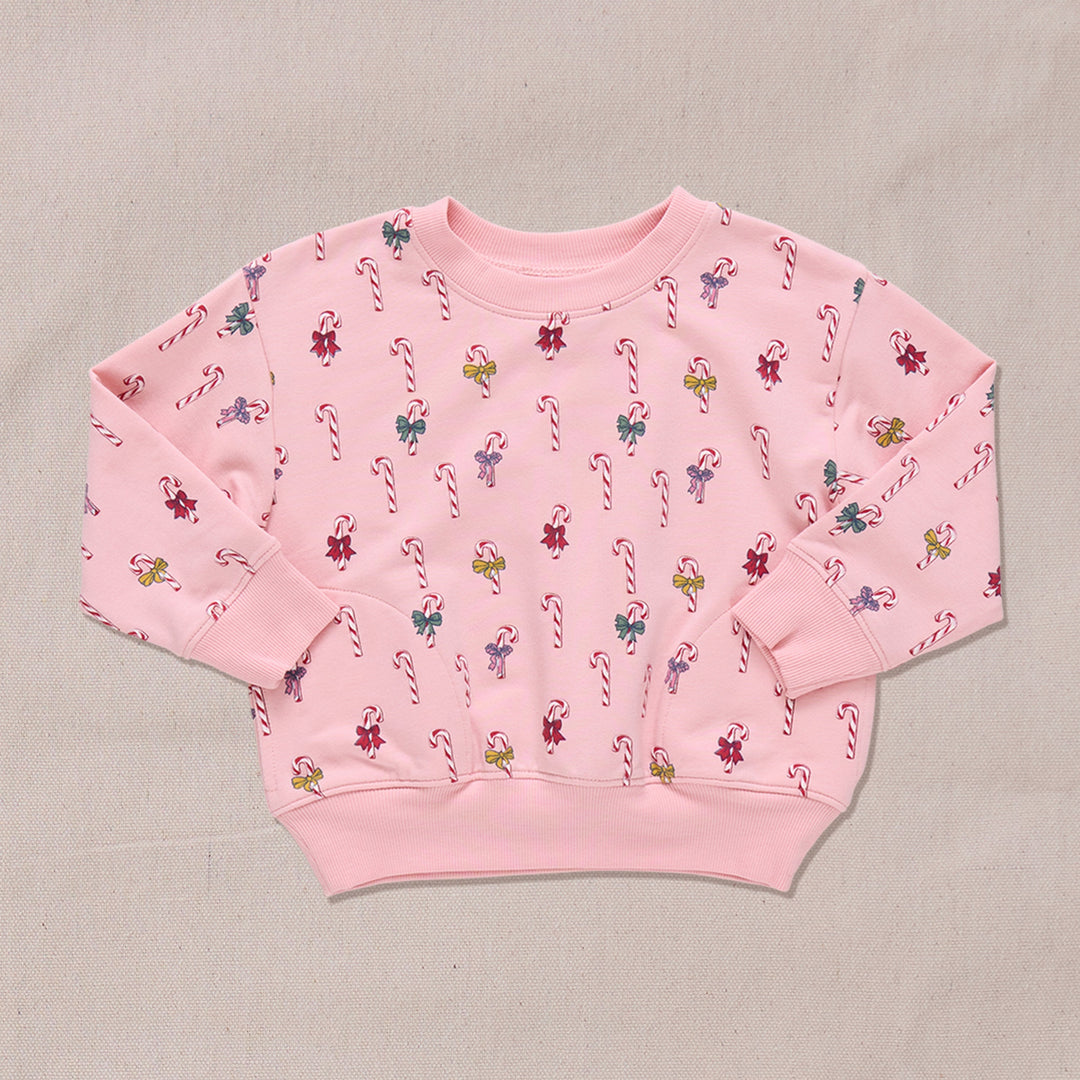 Pink sweatshirt with candy cane and bows pattern on a beige background