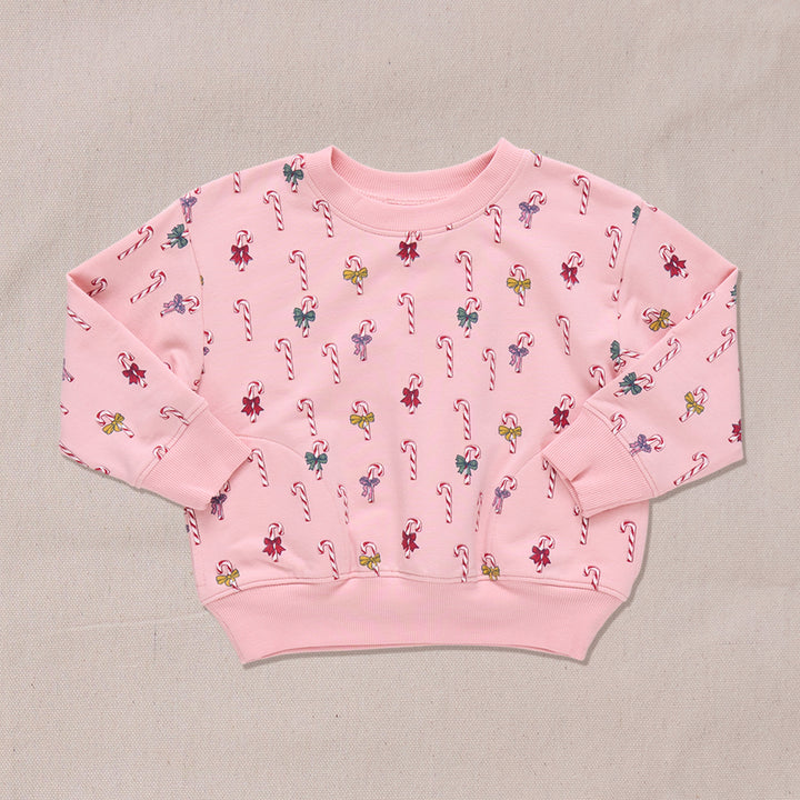 Pink sweatshirt with candy cane and bows pattern on a beige background