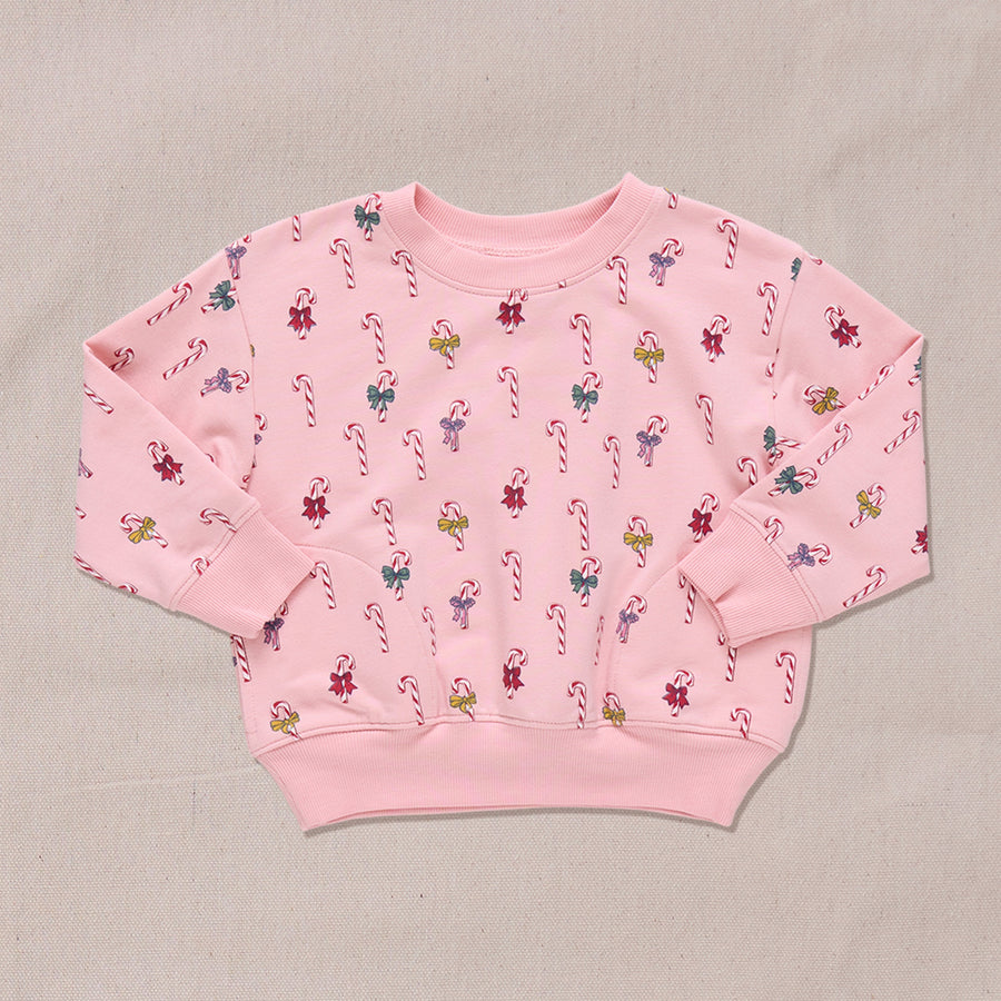 Pink sweatshirt with candy cane and bows pattern on a beige background