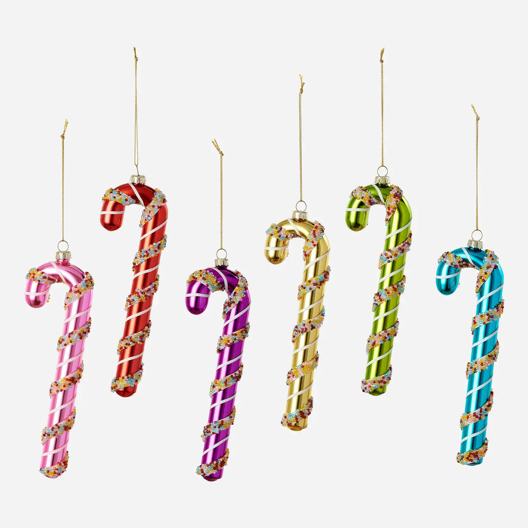 Six candy cane ornaments in pink, red, purple, gold, green, and blue, each decorated with white swirls and colorful sprinkles, hanging against a light gray background.
