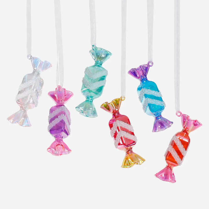 Colorful candy-shaped decorations on white strings against a white background