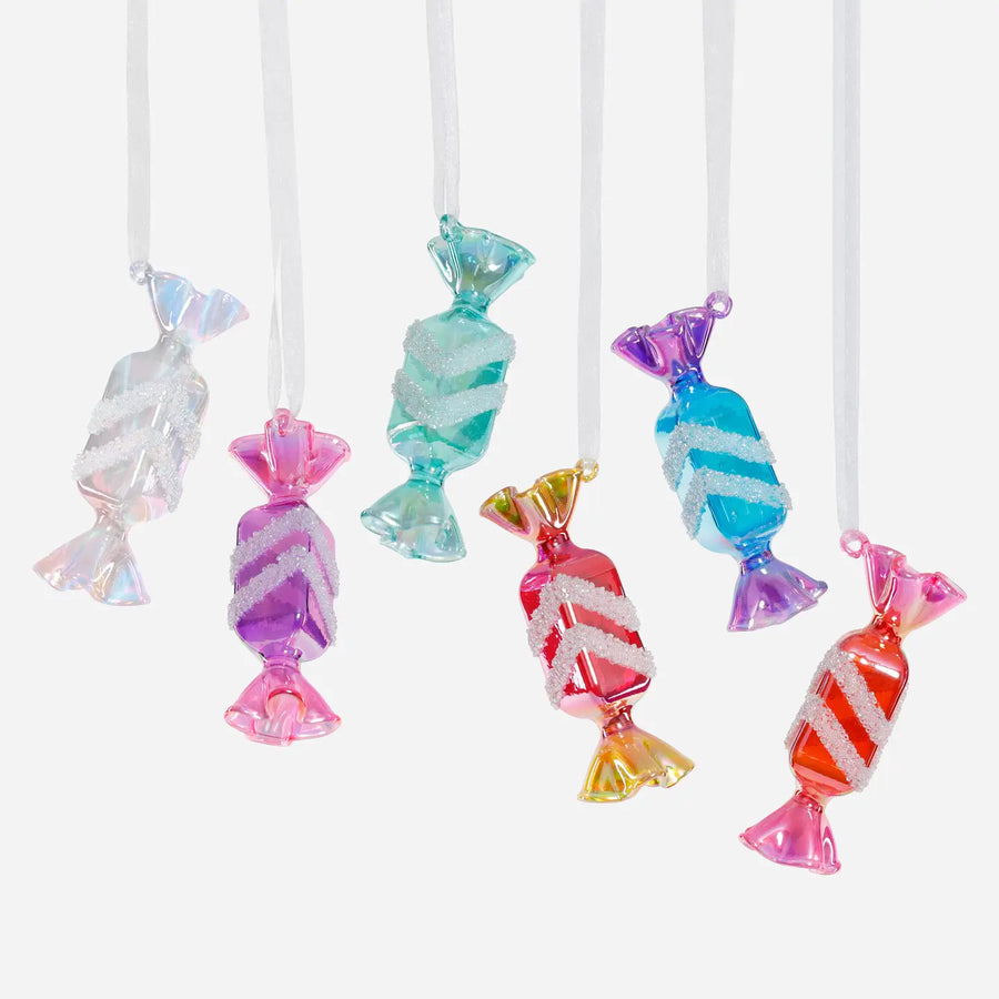 Colorful candy-shaped decorations on white strings against a white background