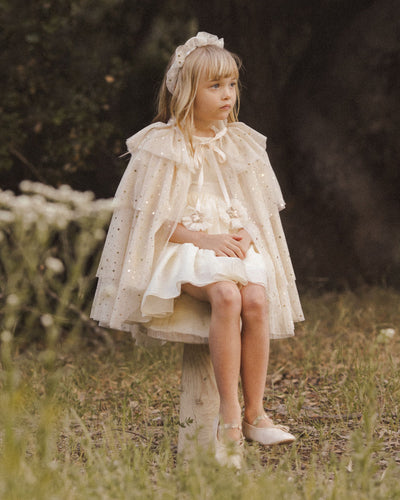 Little girl modeling the champagne cape. ruffled tulle covered in gold stars