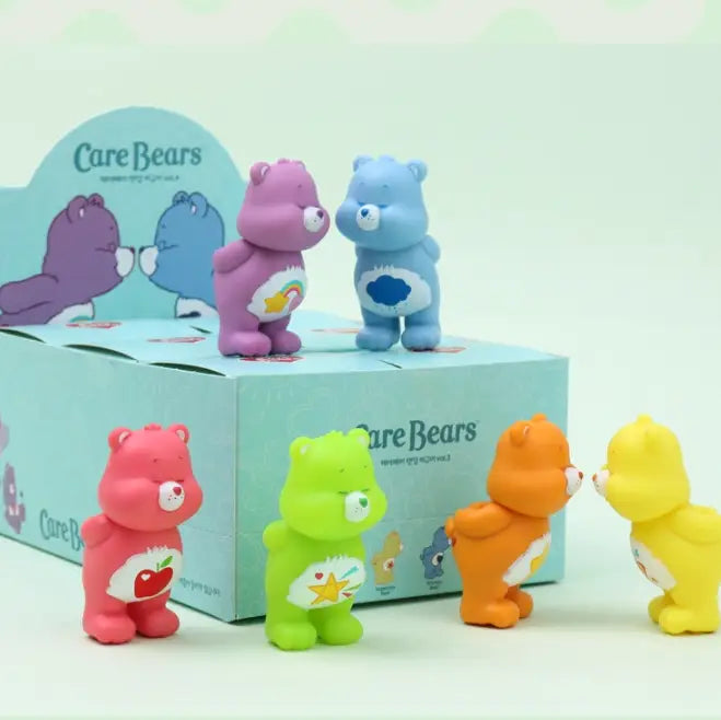 Set of colorful Care Bear figurines in front of a Care Bears branded box.