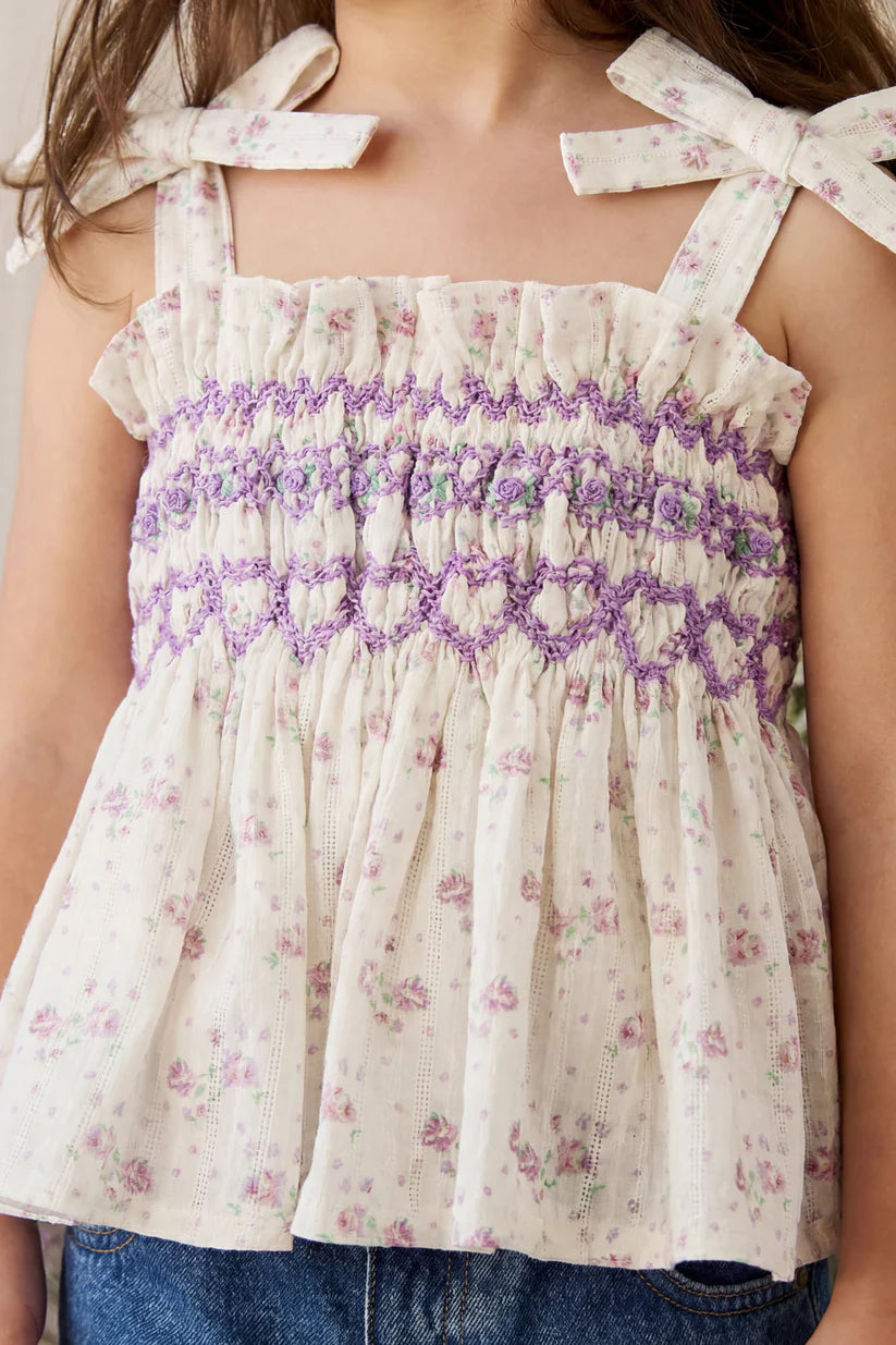Child wearing a floral top with smocked top and bow straps.