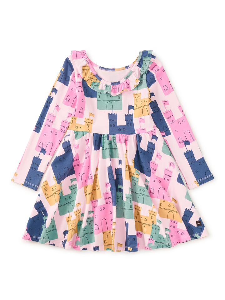A long-sleeve children's dress with a castle pattern in pink, navy blue, mint green, and mustard yellow, featuring a ruffled neckline and a flared skirt.