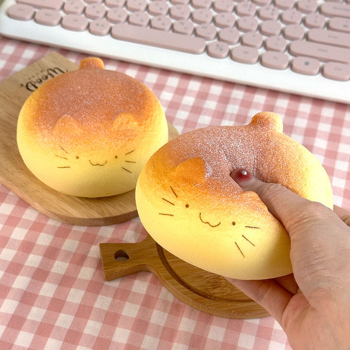 two catbread squishy toys, one hand squeezing the catbread toy 