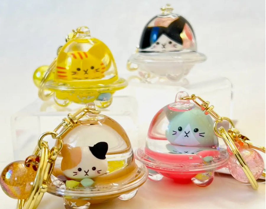 Four cat-themed keychains with transparent domes on a light background