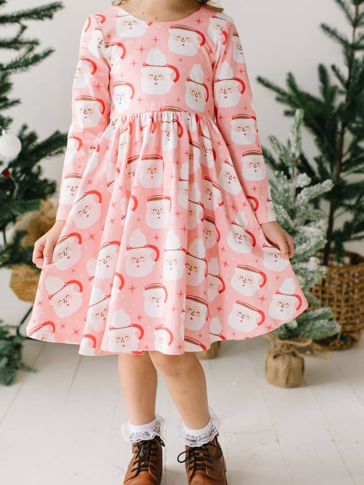 Little girl modeling the santa mug dress with hot cocoa and whipped cream in the mug. dress is pink. 