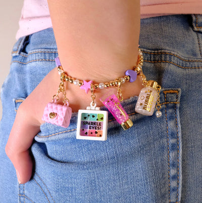 charm bracelet with a few charms on it. girl modeling the look of charms on a stretch bracelet