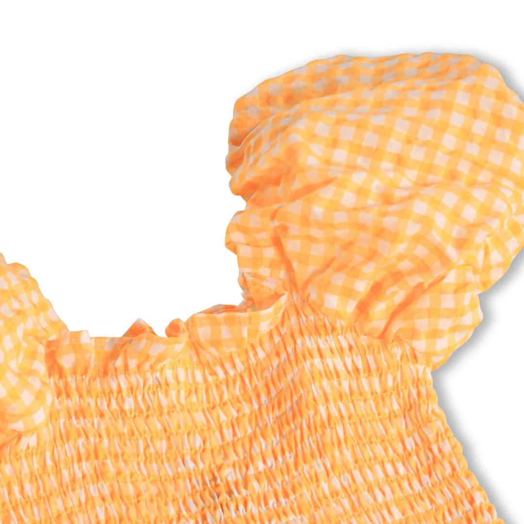Orange gingham dress with ruffled details on a white background