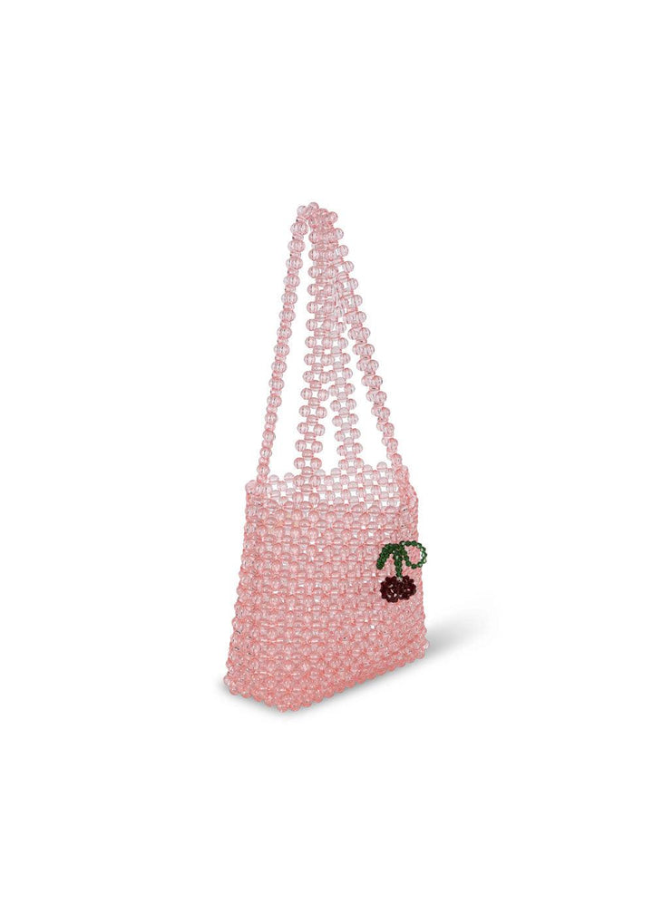 sideview of the pink beaded bag with shoulder strap and beaded cherries attached to the front. 