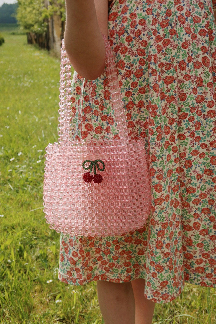 beaded pink bag being modeled by a little girl , she is holding the bag at her elbow. 