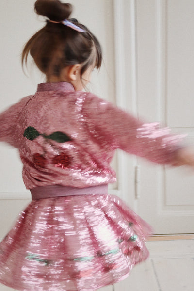 The back of the jacket. The girl is again modeling the jacket and sequin skirt, she is spinning around and you can see the sequins hitting the light. 