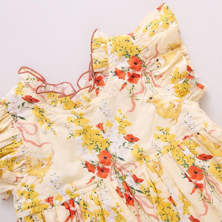 close up view of the baby bubble with ruffle at the collar and sleeves. the print is yellow tiny flowers and orange flowers with little chicks all over