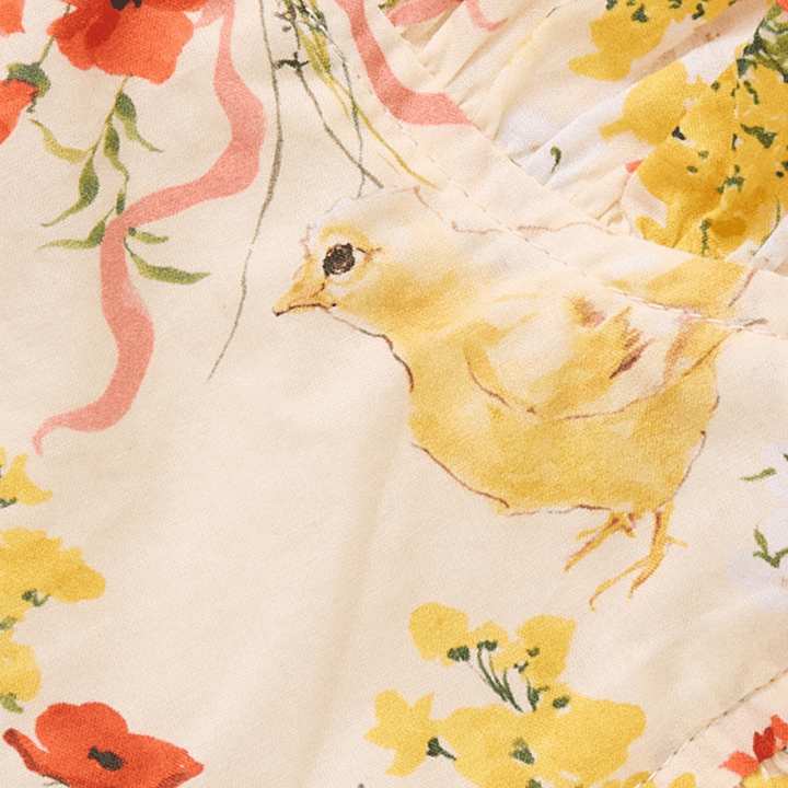 close up of the print. pale yellow color with chicks, flowers and small orange ribbons