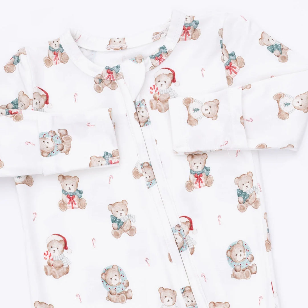 White baby footed sleeper with an all-over print of teddy bears wearing Santa hats and scarves, arranged in a flat-lay pattern.