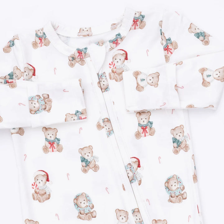 White baby footed sleeper with an all-over print of teddy bears wearing Santa hats and scarves, arranged in a flat-lay pattern.