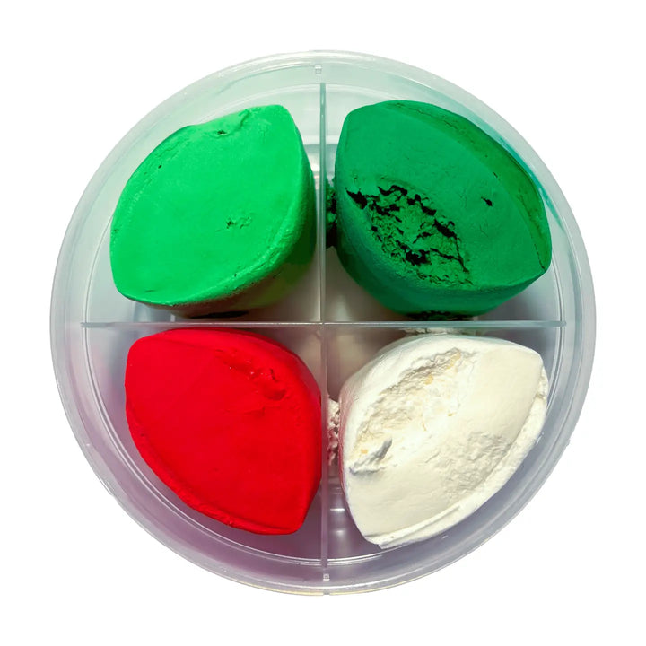 Four makeup crayons in a clear plastic four-compartment container, featuring shades of bright green, dark green, red, and white, set against a plain white background.
