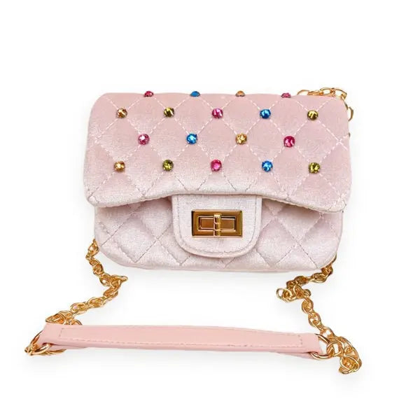 A light pink quilted velvet handbag with colorful rhinestone embellishments, a gold-tone turn-lock clasp, and a gold chain strap with a pink wristlet, shown on a plain white background.