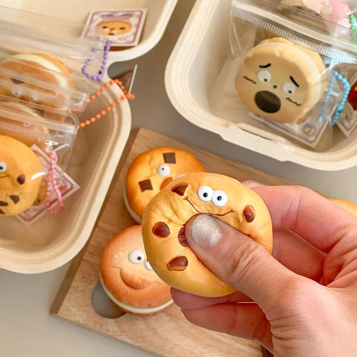 Hand holding a small food item on a keychain with facial features, surrounded by similar items in packaging.