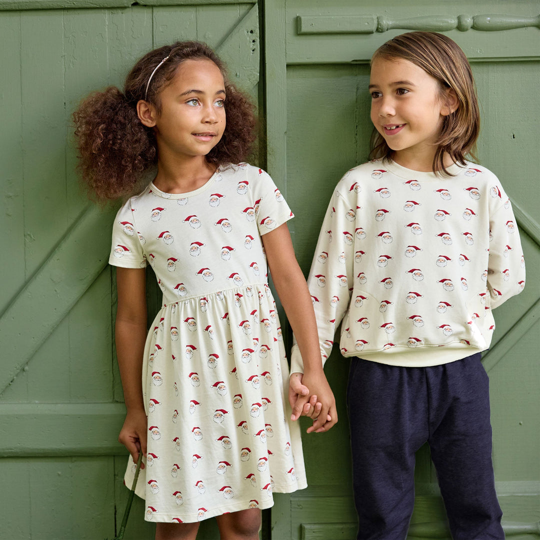 little kids wearing holiday outfits with santa prints 