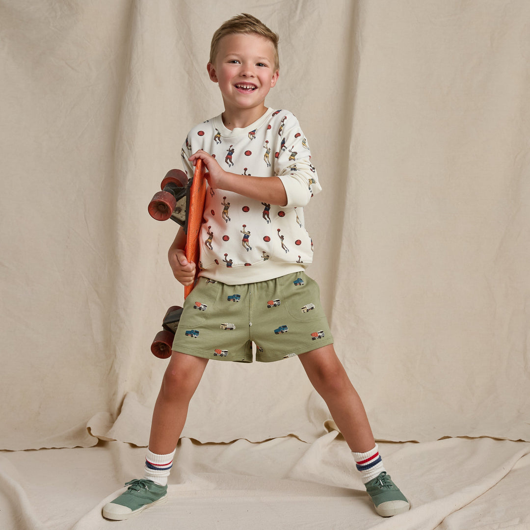 Child holding a toy skateboard against a plain background