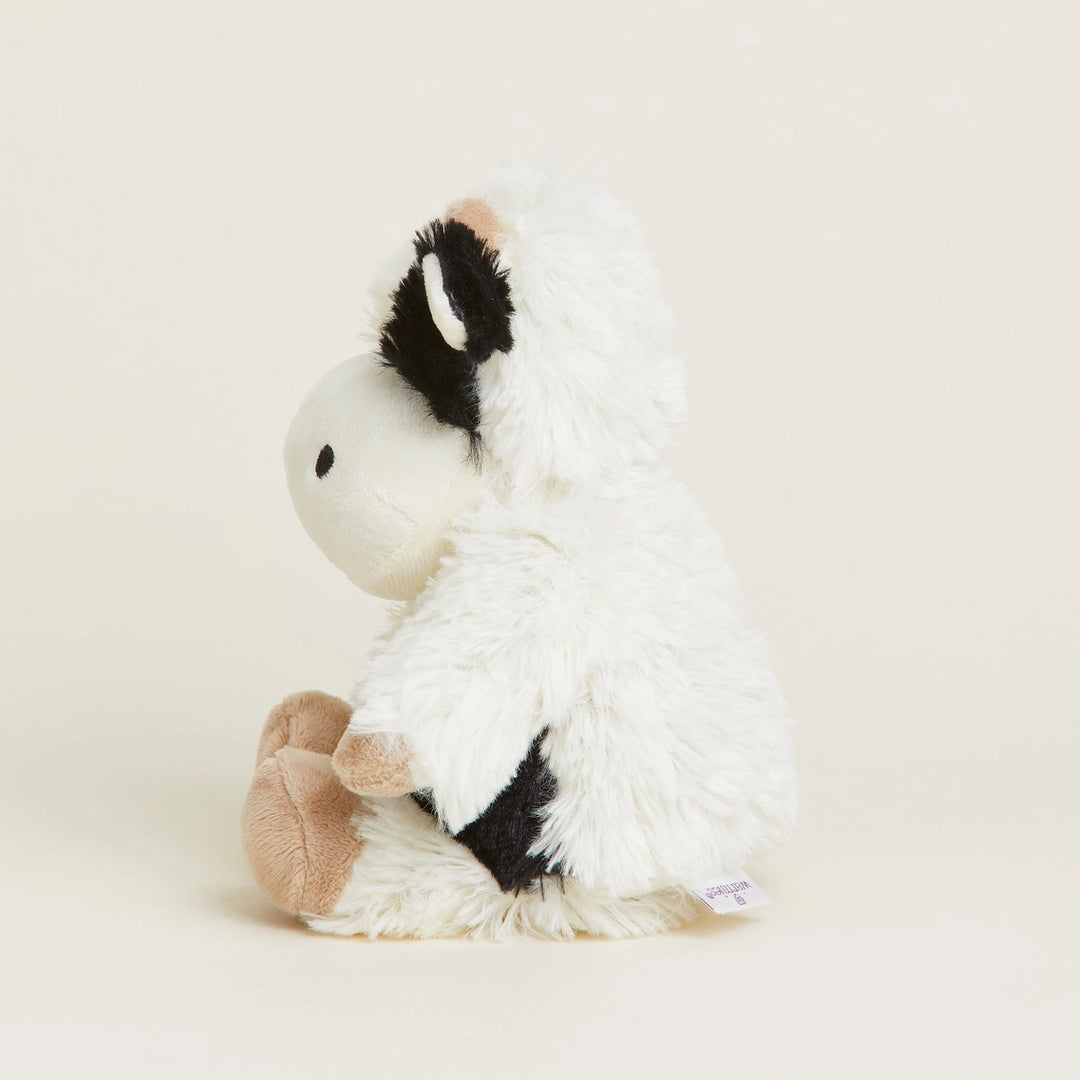White plush toy with black and brown accents on a beige background