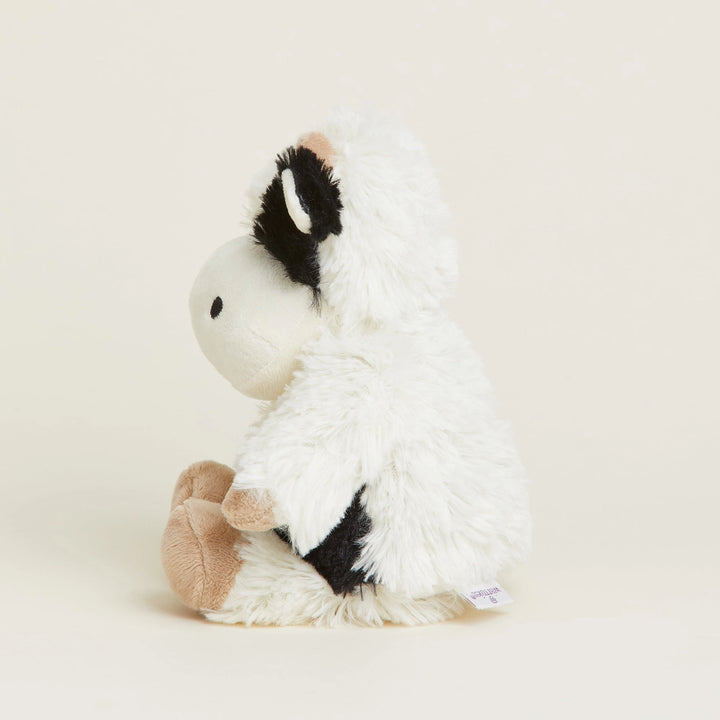 White plush toy with black and brown accents on a beige background