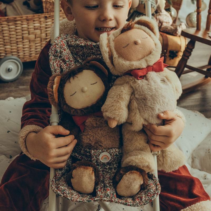 child playing with both baby dolls dressed as teddy bears in the stroller