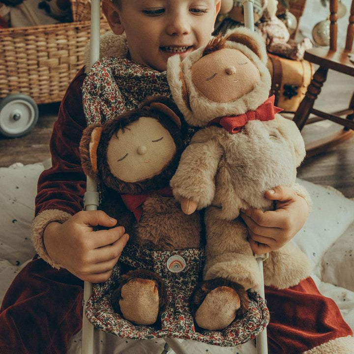 child playing with both baby dolls dressed as teddy bears in the stroller