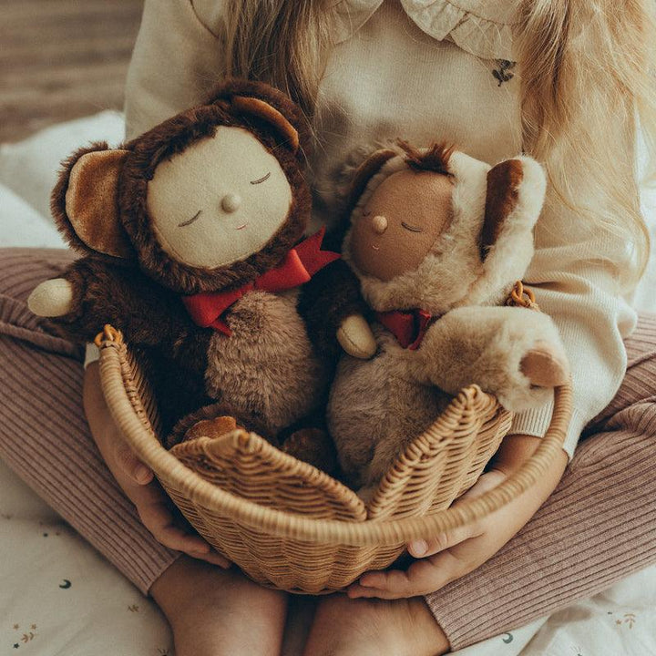 2 baby dolls dressed as teddy bears sitting in a basket cuddled together