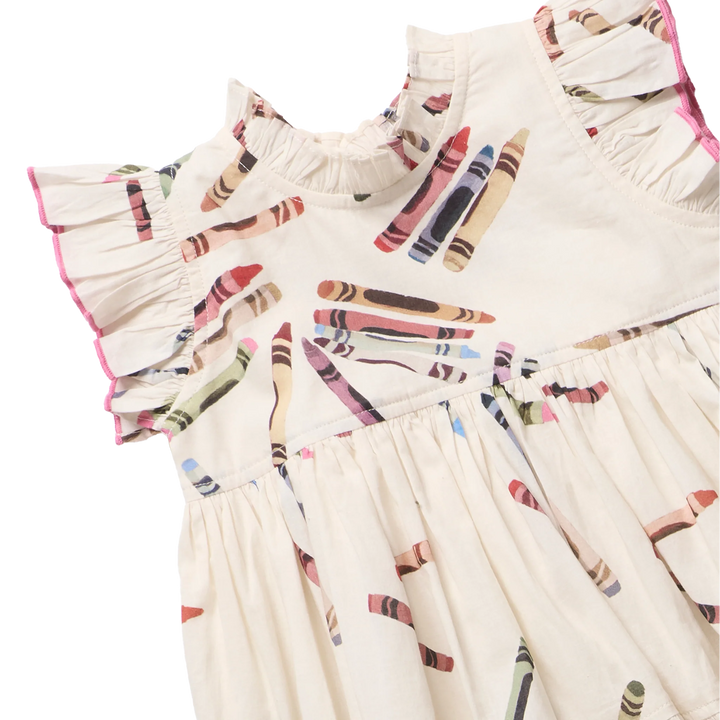A cream-colored sleeveless dress with ruffled shoulders and a gathered skirt, printed with a colorful crayon pattern. The dress has pink piping along the ruffled sleeve edges and is shown against a plain white background.