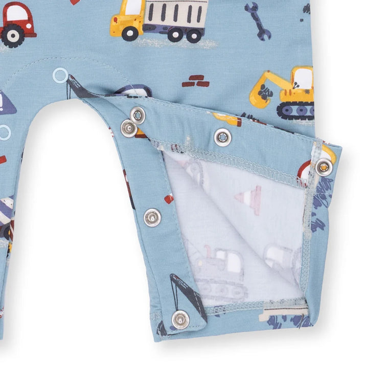 Children's romper with construction vehicle pattern on a blue background. this shows the snaps on the legs of the romper