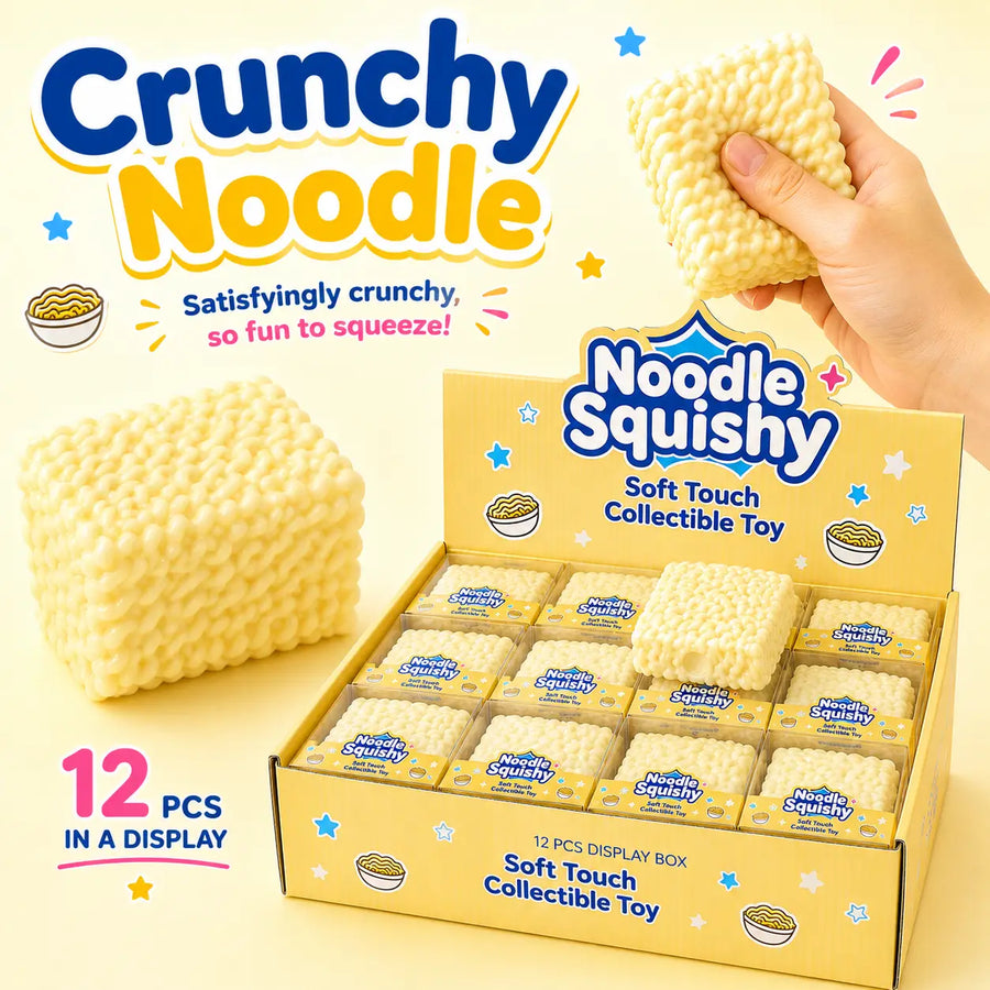 A display box of Crunchy Noodle 'Noodle Squishy' soft touch collectible toys, with a hand holding one of the textured yellow cube-shaped toys. The packaging is yellow and blue, and the background is a light pastel yellow.