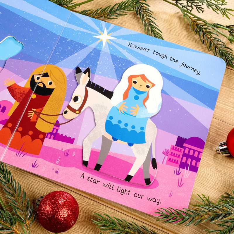 Children's book with illustrations of a man, woman, and horse on a wooden surface with Christmas decorations.