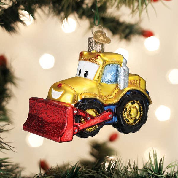 Decorative bulldozer ornament on a Christmas tree with blurred lights in the background